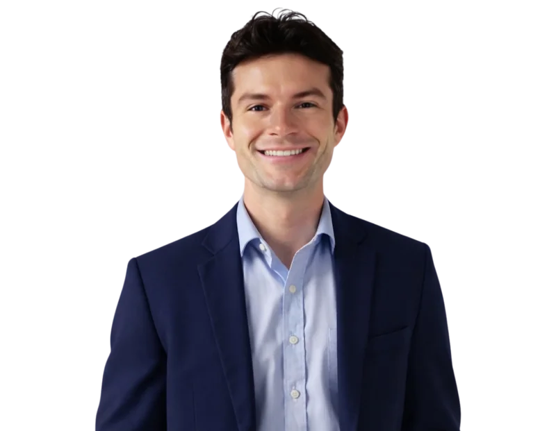 Professional headshot of Benjamin Rowley smiling, wearing a navy blue suit with a light blue dress shirt posed against a softly blurred light background.