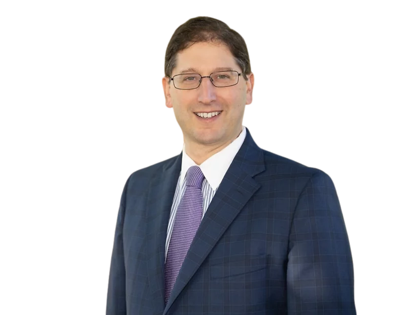 Professional headshot of a smiling Justin Coffey in a blue checkered suit and purple tie.