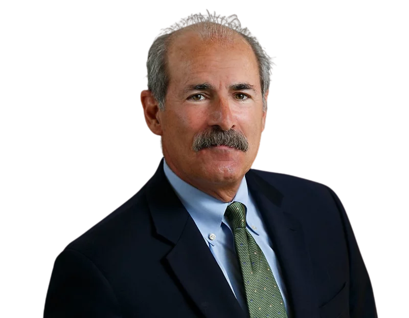Bill Principe wearing a dark suit, light blue shirt, and green tie against a plain background.
