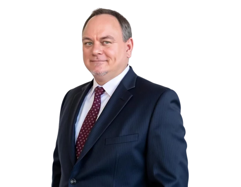 Jack Wallace stands in a dark pinstripe suit and maroon patterned tie, smiling slightly with a confident and approachable demeanor. He has short-cropped hair and a neatly groomed goatee, dressed professionally against a plain background.