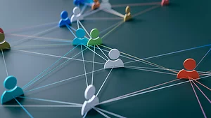 3D illustration of colorful human icons connected by thin lines across a dark surface, representing a network of relationships or communication. The arrangement symbolizes collaboration, teamwork, and interconnected digital or social systems.